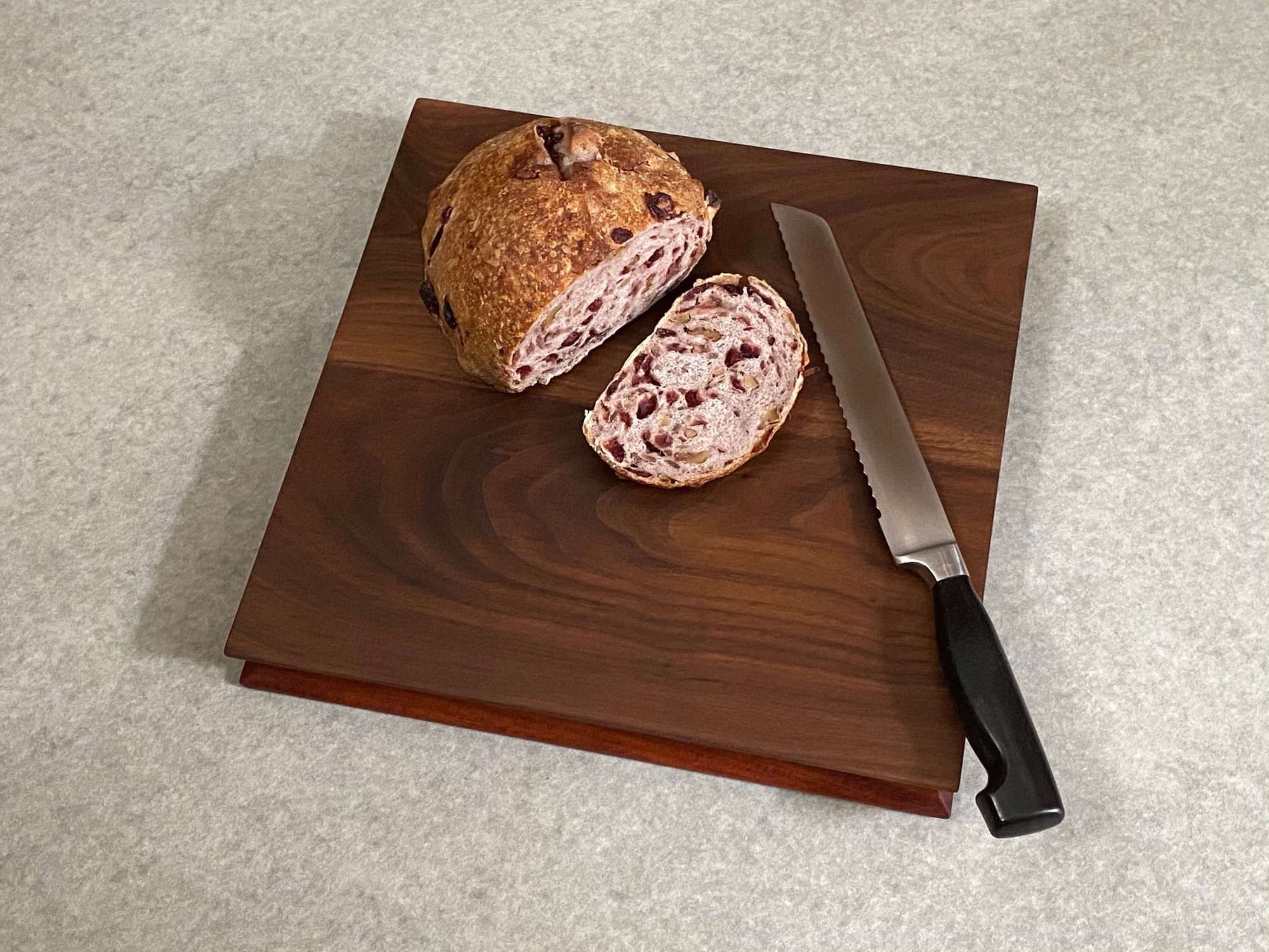 Square cutting and serving board made of mahogany on one side and walnut on the reverse. Sculpted edges provide comfortable fingerholds.