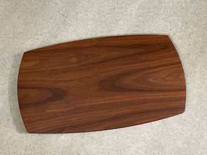 A large rounded rectangular cutting and serving board made of walnut. Sculpted edges provide comfortable fingerholds.
