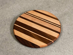 Small round cutting and serving board of maple and walnut stripes.
