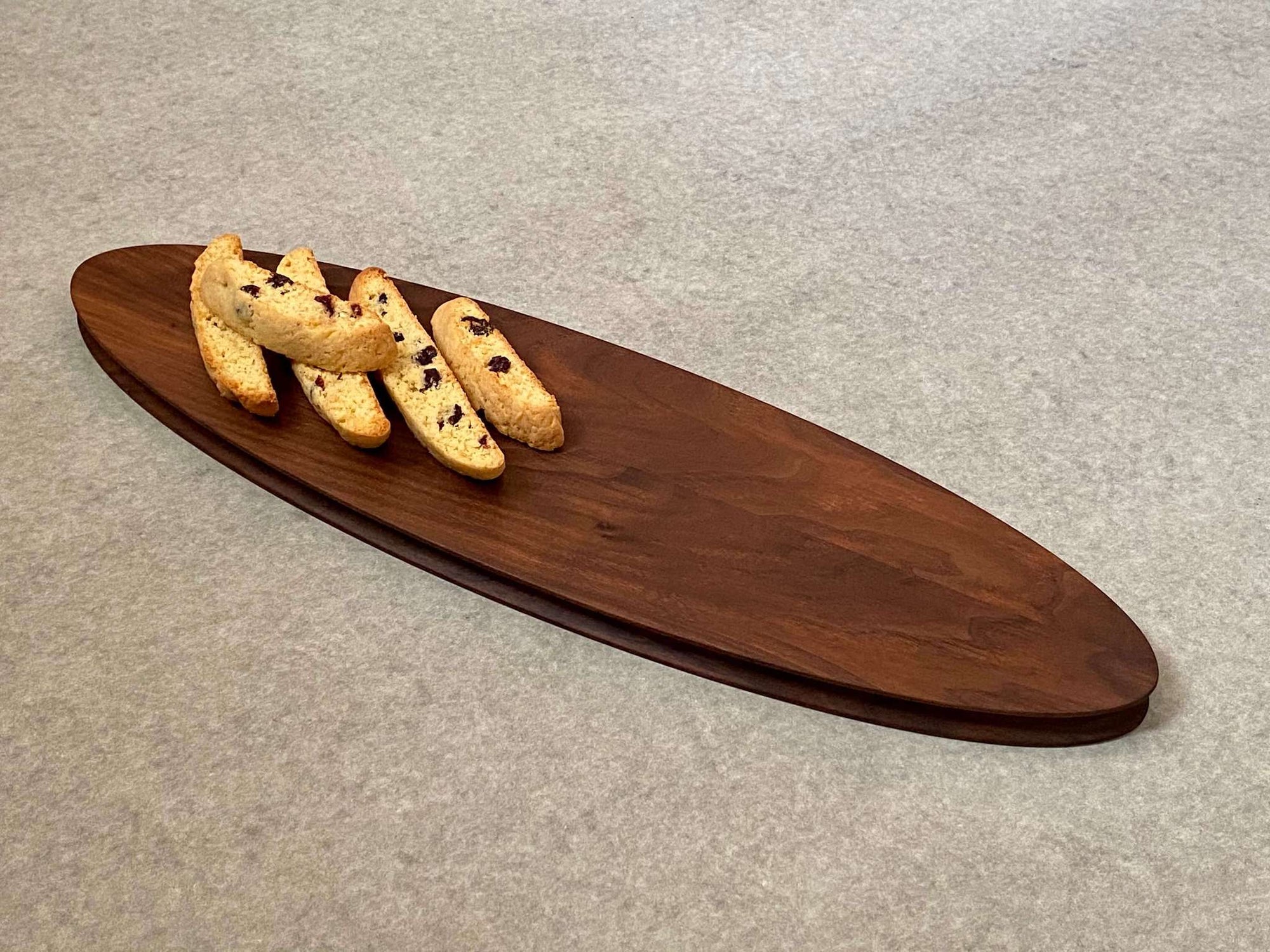 Long oval cutting and serving board made of walnut. Sculpted edges add a nice detail.