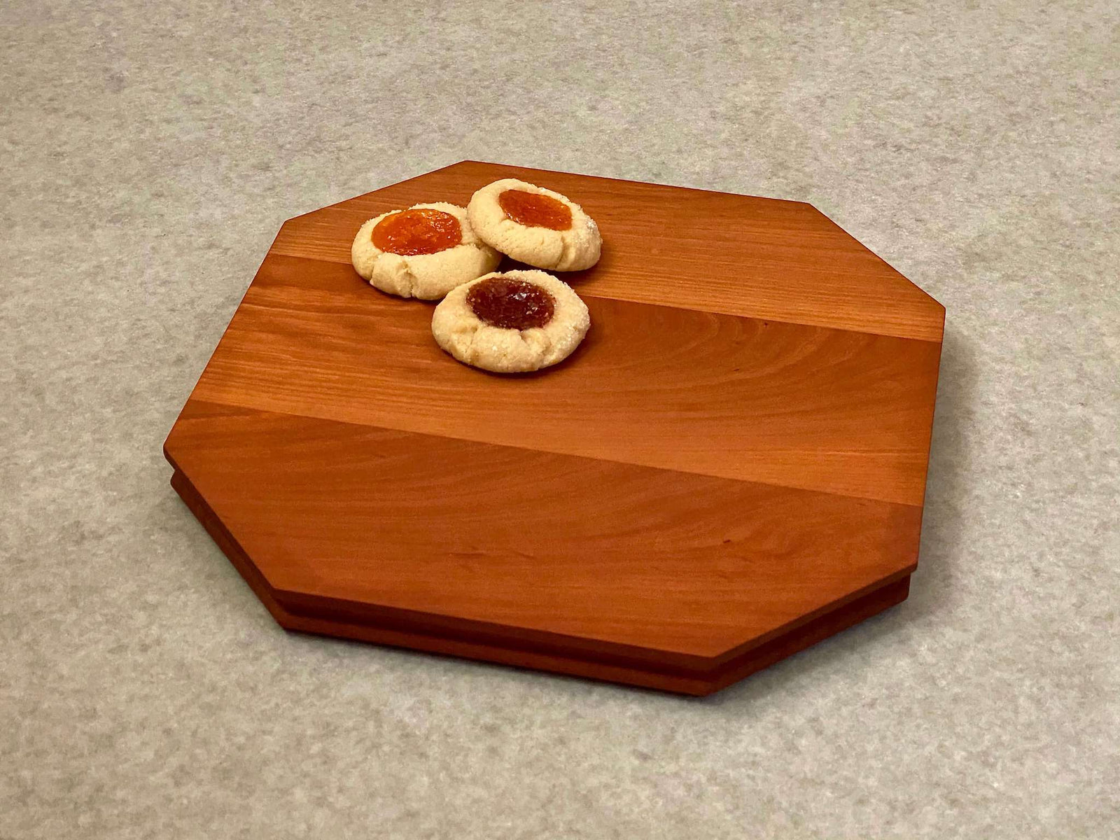 Octagonal shaped cutting and serving board made of cherry. Sculpted edges provide comfortable fingerholds.