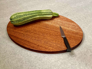 Oval shaped cutting and serving board in mahogany. Sculpted edges provide comfortable fingerholds.