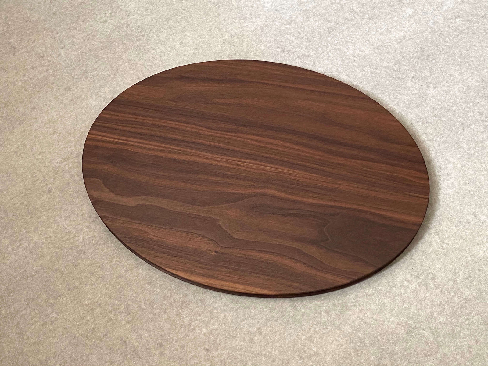 Oval shaped cutting and serving board in mahogany. Sculpted edges provide comfortable fingerholds.
