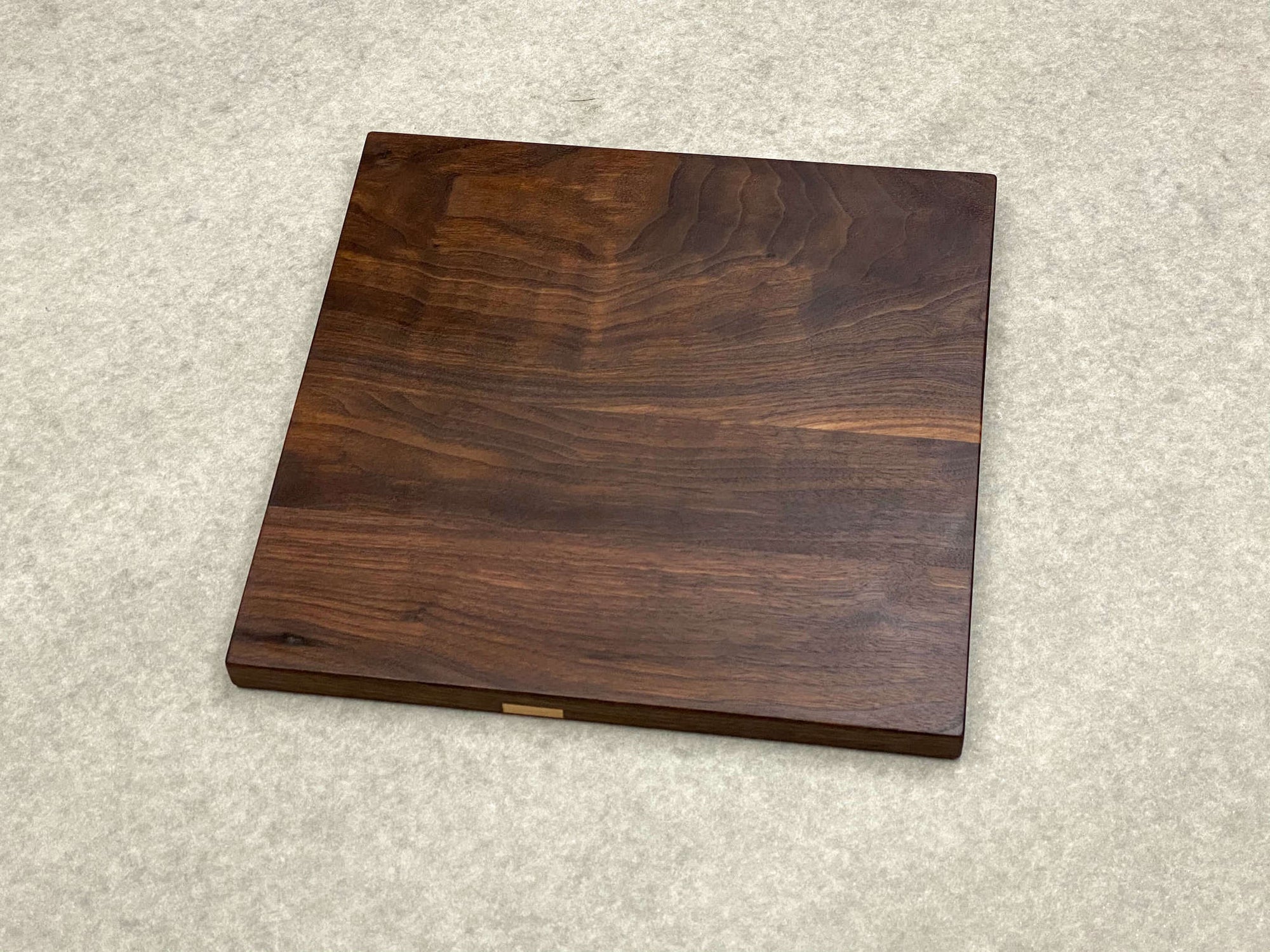 Square cutting and serving board in walnut with inlaid maple dots.