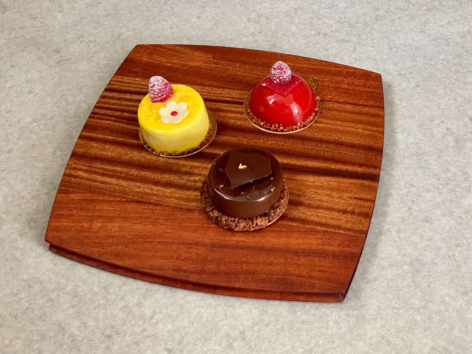 A rounded square cutting and serving board in mahogany. Sculpted edges provide a nice detail.