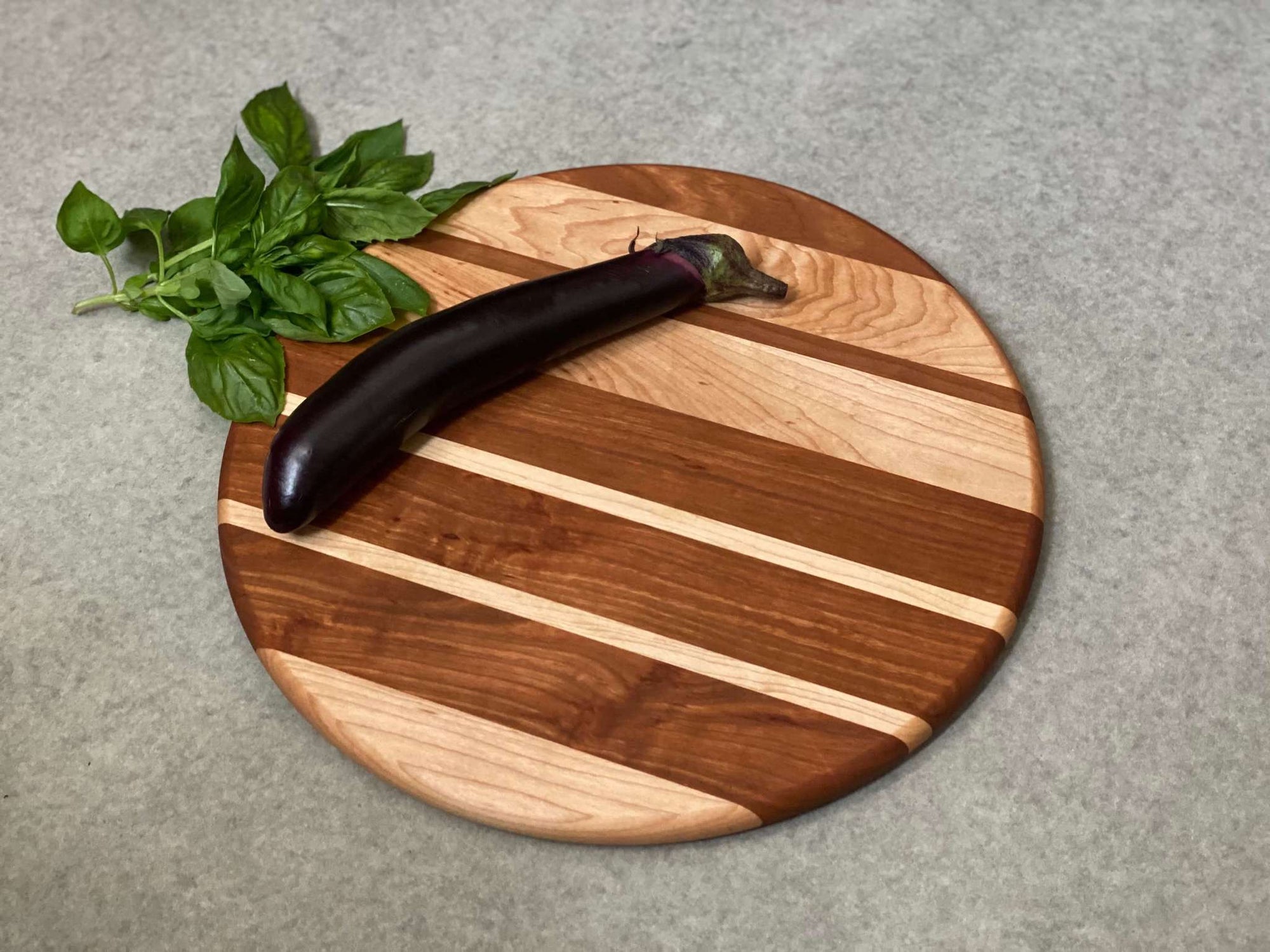 Round cutting and serving board of thick and thin stripes of cherry and maple.
