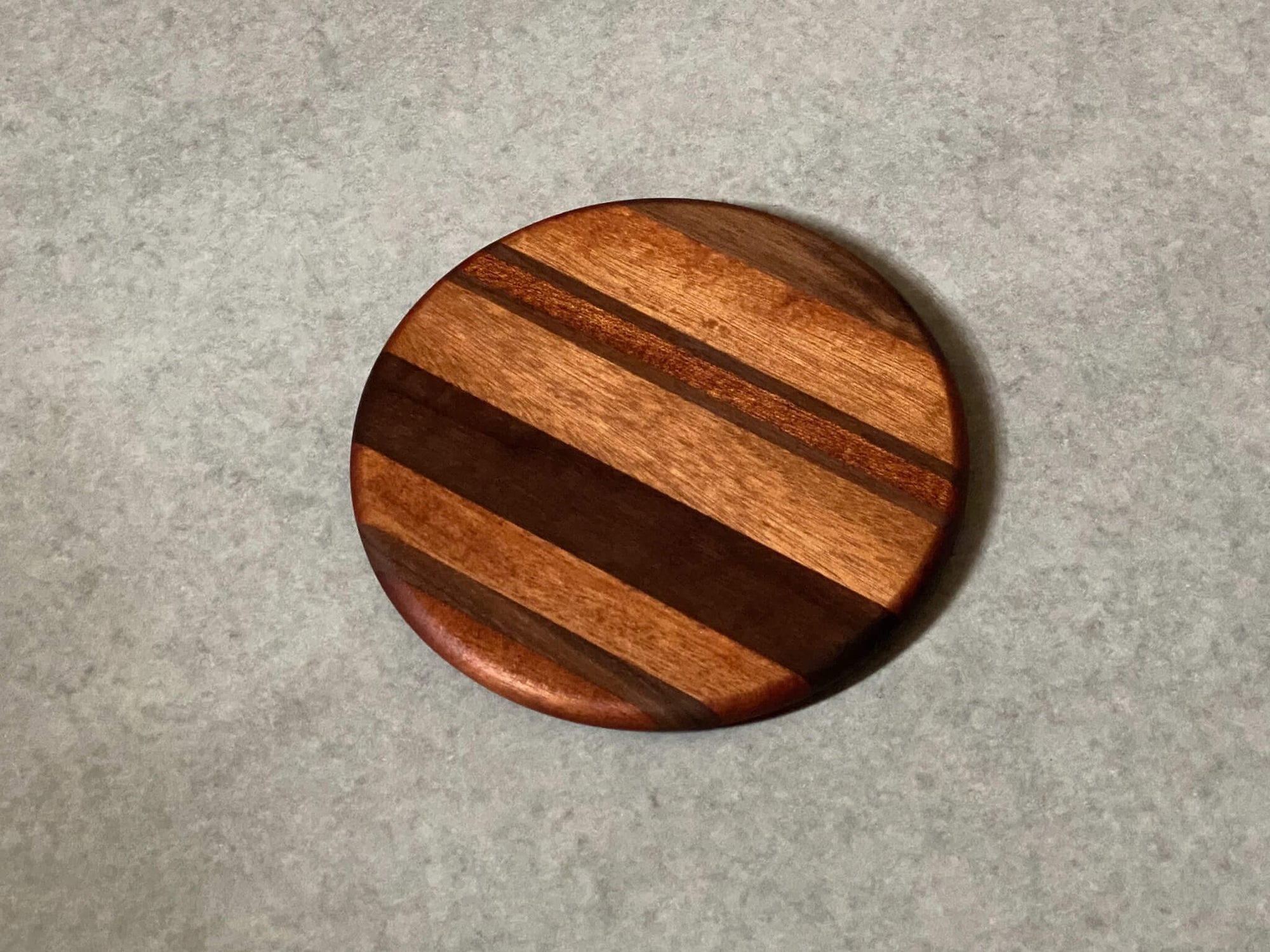 Small round cutting and serving board of maple and mahogany stripes.