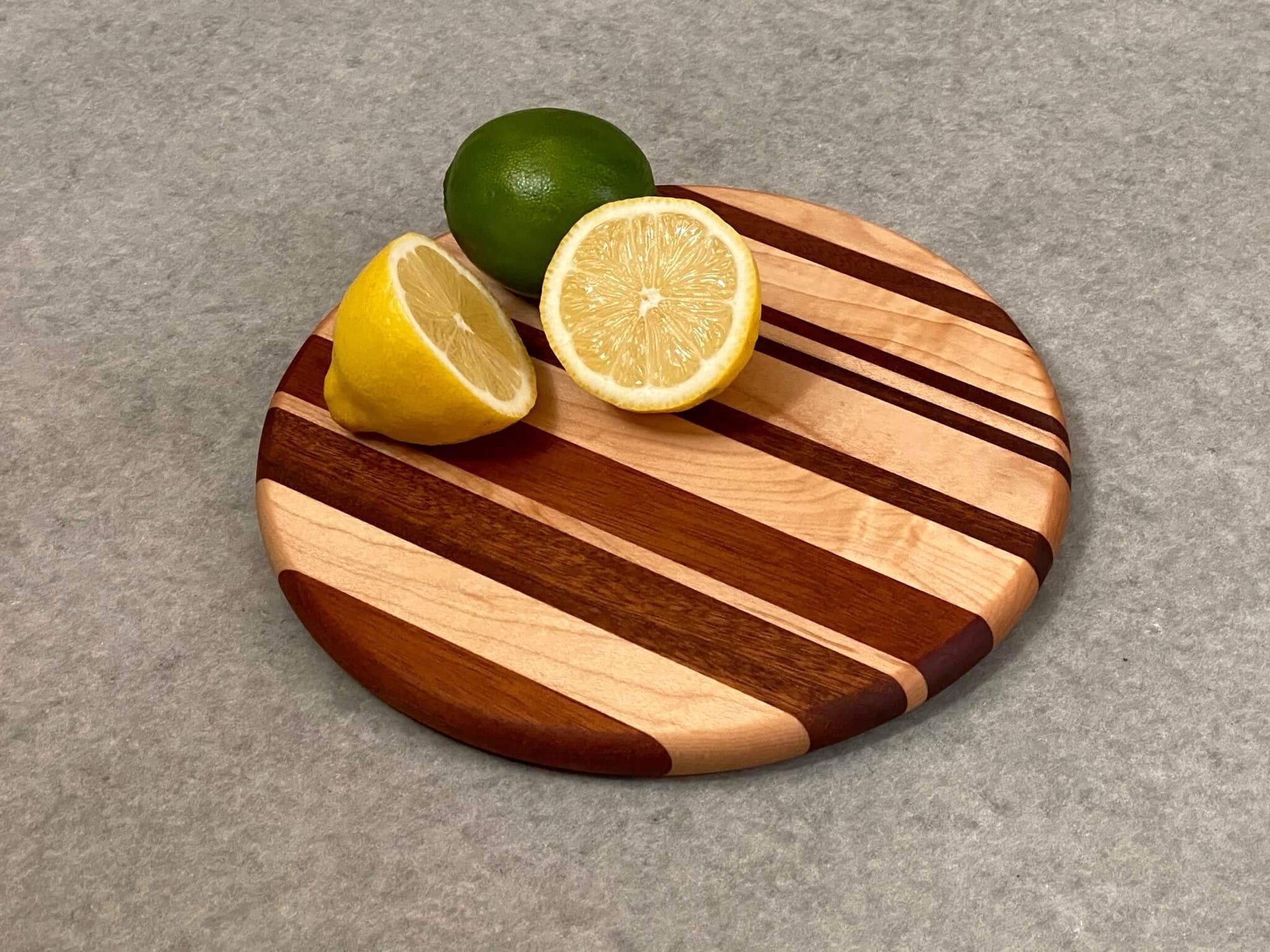 Small round cutting and serving board of maple and mahogany stripes.