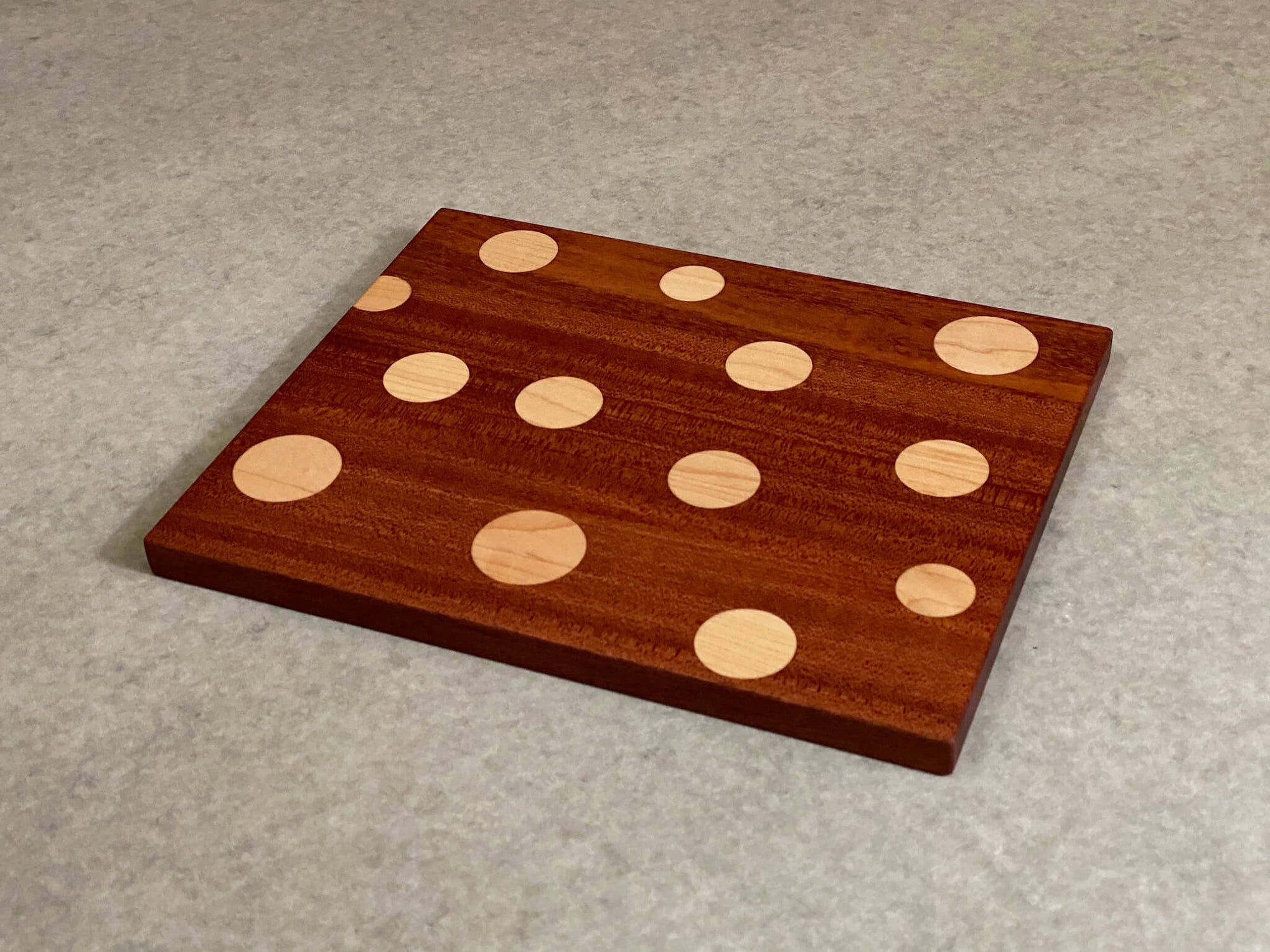 Small rectangular board of walnut with inlaid polka dots of maple. Pattern is on both sides.